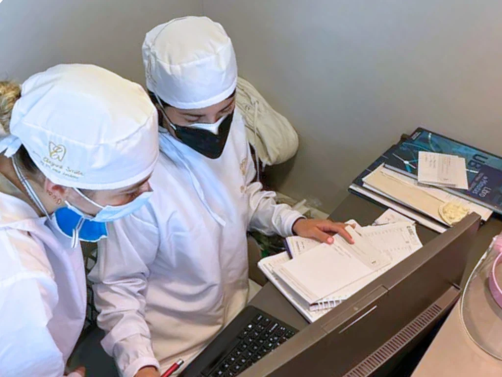 Two healthcare workers in protective gear reviewing documents.